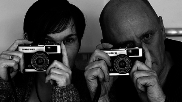 Two men trying to take a picture from a vintage camera